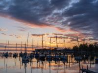 Glühende Wolkenstreifen am Himmel über den Bootsstegen am Chiemsee bei Bernau-Felden